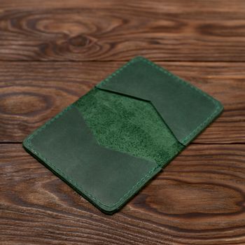 Handmade green emerald leather cardholder on wooden background. Stock photo with blurred background.