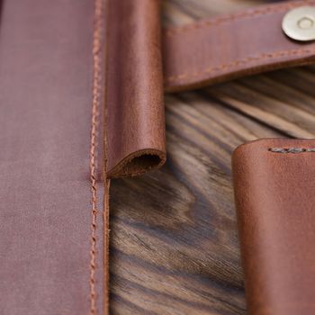 Part og red color handmade leather notebook cover on wooden background. Stock photo of luxury business accessories.