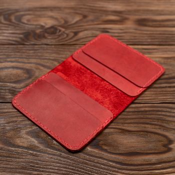 Handmade red leather cardholder on wooden background. Cardholder have 4 pockets for cards. Stock photo with soft focus background.