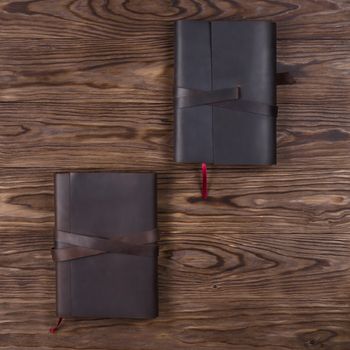 Black and brown handmade leather notebook cover with notebook on wooden background. Stock photo of luxury business accessories. Up to down view.