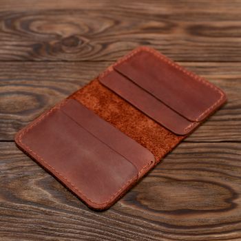 Handmade ginger colour leather cardholder on wooden background. Cardholder have 4 pockets for cards. Stock photo with soft focus background.