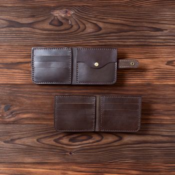 Two brown handmade leather wallets on wooden textured background. Up to down view. Wallet stock photo.