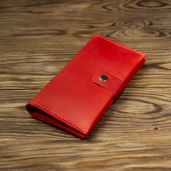 Hue red color handmade leather wallet on textured wooden background. Wallet is unisex. Side view. Stock photo of luxury accessories.