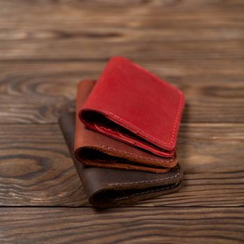 Three two-pocket leather handmade cardholder. Cardholders lies one on another. Stock photo on blurred background.