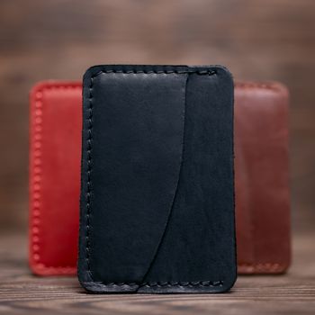 One pocket black leather handmade cardholder. On blurred background stay other colour cardholders. Stock photo on blurred background.
