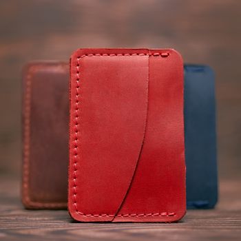 One pocket red leather handmade cardholder. On blurred background stay other colour cardholders. Stock photo on blurred background.