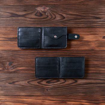 Two black handmade leather wallets on wooden textured background. Up to down view. Wallet stock photo.