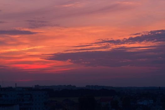 Orange evening sky with blurred sun on horizon trough fence. Creative idea- underexposed photo.