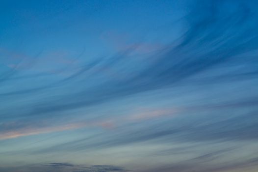 Blue evening sky with blurred sun on horizon trough fence. Creative idea- underexposed photo.