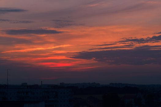 Orange evening sky with blurred sun on horizon trough fence. Creative idea- underexposed photo.