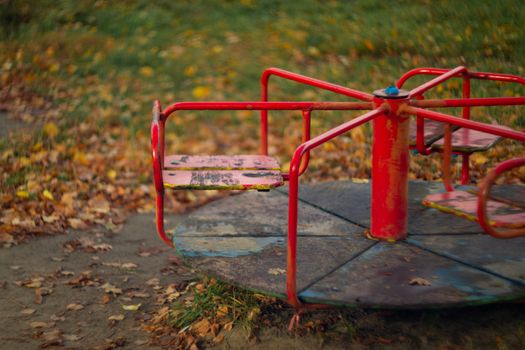 Baby swing in the fall in the park in wet weather