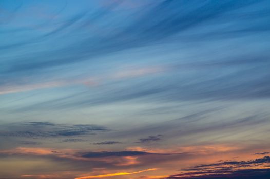 Blue evening sky with blurred sun on horizon trough fence. Creative idea- underexposed photo.