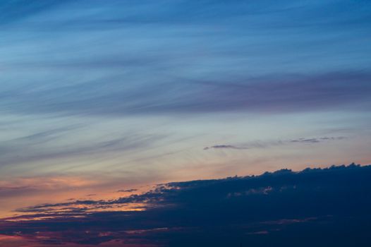 Blue evening sky with blurred sun on horizon trough fence. Creative idea- underexposed photo.