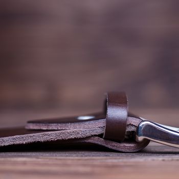 Brown handmade belt buckle lies on textured wooden background closeup. Side view. Stock photo of businessman accessories with blurred background.