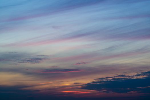 Blue evening sky with blurred sun on horizon trough fence. Creative idea- underexposed photo.