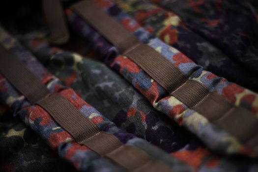 Military camouflage roomy backpack. In the frame of the strap and the back of a backpack. Close-up view.