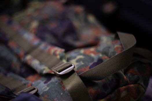 Military camouflage roomy backpack. In the frame of the strap and the back of a backpack. Close-up view.