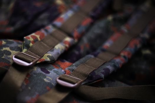 Military camouflage roomy backpack. In the frame of the strap and the back of a backpack. Close-up view.