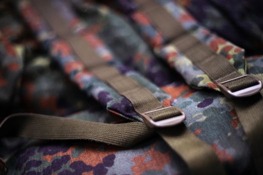 Military camouflage roomy backpack. In the frame of the strap and the back of a backpack. Close-up view.