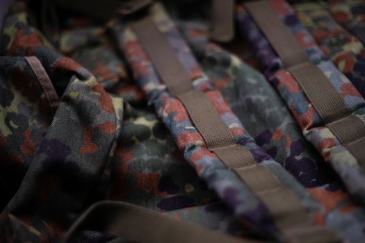 Military camouflage roomy backpack. In the frame of the strap and the back of a backpack. Close-up view.
