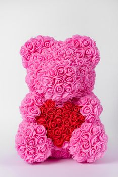 Pink teddy bear toy of foamirane roses. Red heart in teddy paws. Stock photo isolated on white background.