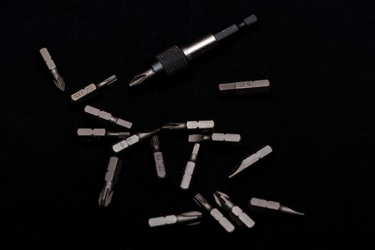 Tool carbon steel bits with bit holder on black background in dark key style.