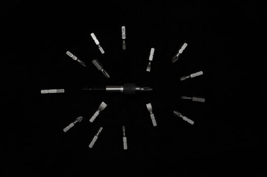 Tool carbon steel bits on black background in dark key style. Bit holder in center and bits around bit holder.