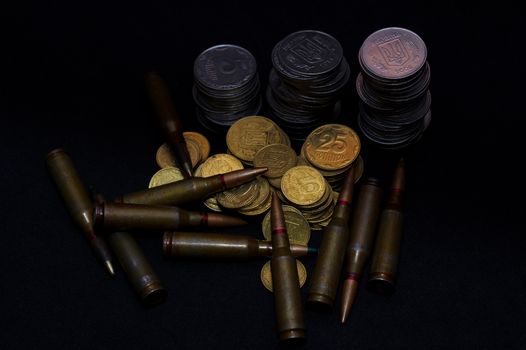 Ukrainian small coins with rifle military ammo on black background. Symbolizes war for money- biggest problem in world.