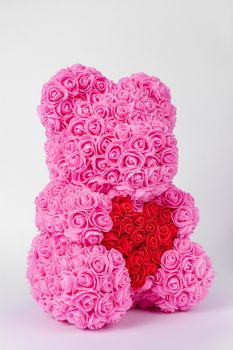 Pink teddy bear toy of foamirane roses. Red heart in teddy paws. Stock photo isolated on white background.
