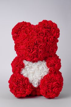 Red  teddy bear of foamirane roses. White heart in teddy paws. Stock photo isolated on white background.