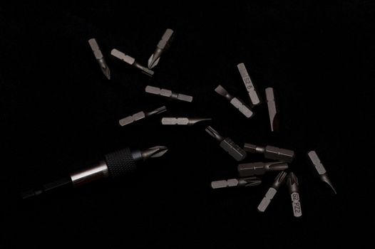 Tool carbon steel bits with bit holder on black background in dark key style.