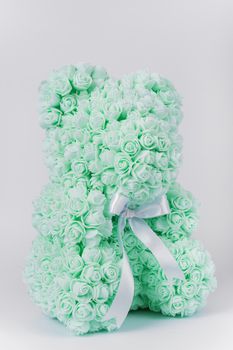 Green teddy bear toy of foamirane roses. White stripe on teddy neck. Stock photo isolated on white background. Gift on holiday for women.