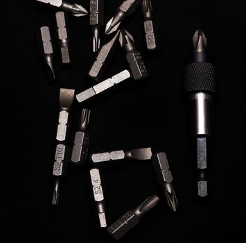 Tool carbon steel bits with bit holder on black background in dark key style.