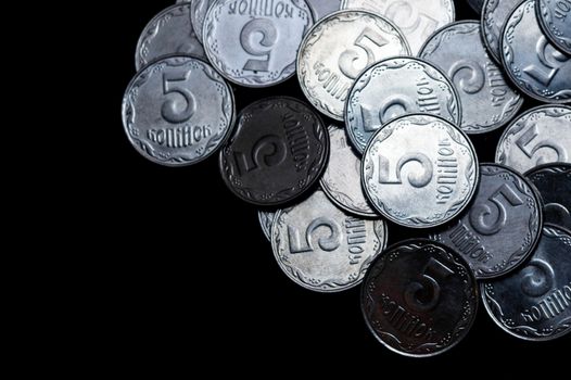 Ukrainian coins isolated on black background. Close-up view. Coins are located above the right side of frame. A conceptual image.
