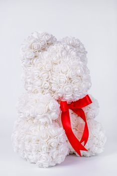 White teddy bear toy of foamirane roses. Red stripe on teddy neck. Stock photo isolated on white background. Gift on holiday for women.