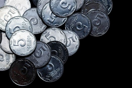Ukrainian coins isolated on black background. Close-up view. Coins are located above the left side of frame. A conceptual image.