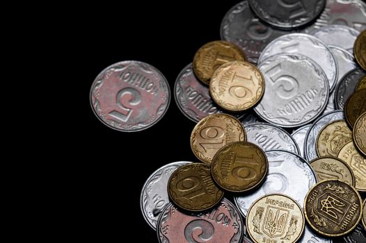 Ukrainian coins isolated on black background. Close-up view. Coins are located above the right side of frame. A conceptual image.