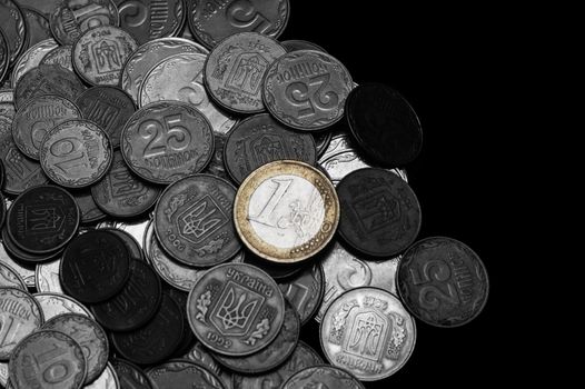Ukrainian coins with one euro coin isolated on black background. Black and white image. Euro coin is colored. Close-up view. Coins are located at the left side of frame. A conceptual image.