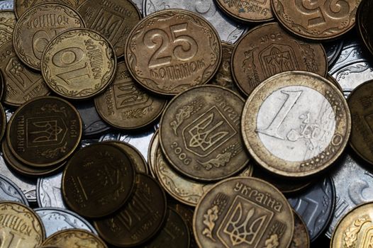 Ukrainian coins with one euro coin isolated on black background. Close-up view. Coins are located at center of frame. A conceptual image.