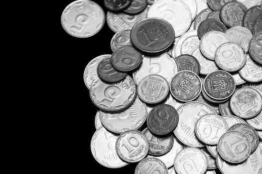Ukrainian coins with one euro coin isolated on black background. Black and white image. Close-up view. Coins are located at the right side of frame. A conceptual image.