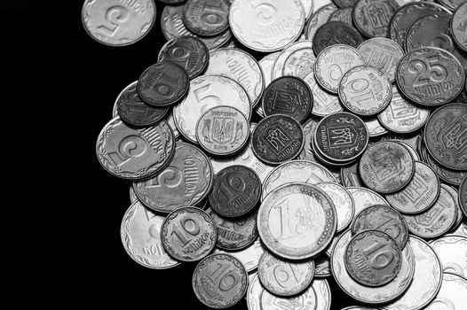 Ukrainian coins with one euro coin isolated on black background. Black and white image. Close-up view. Coins are located at the right side of frame. A conceptual image.