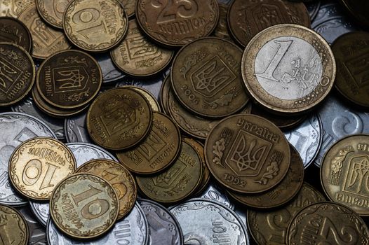 Ukrainian coins with one euro coin isolated on black background. Close-up view. Coins are located at center of frame. A conceptual image.