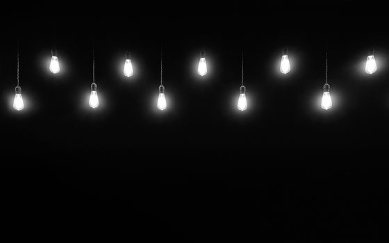 Hanging light bulbs on black background with copy space, black and white photography