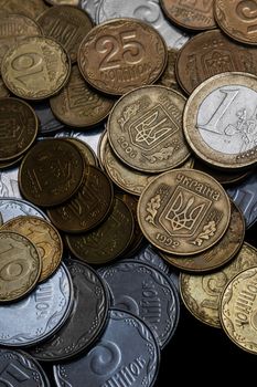Ukrainian coins with one euro coin isolated on black background. Close-up view. Coins are located at center of frame. A conceptual image.