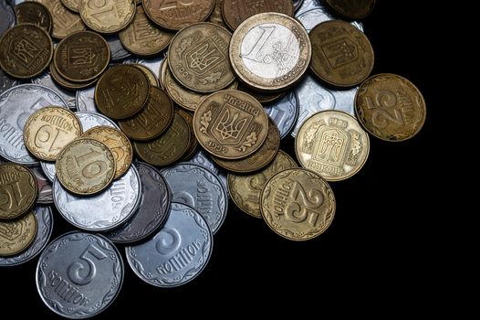 Ukrainian coins with one euro coin isolated on black background. Close-up view. Coins are located at the left side of frame. A conceptual image.