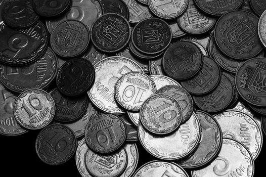 Ukrainian coins isolated on black background. Close-up view. Black and white image. Coins are located above the center of frame. A conceptual image.