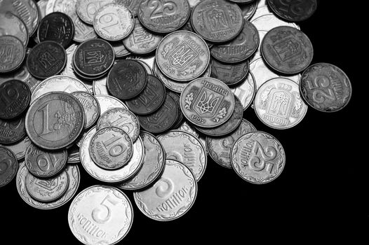 Ukrainian coins with one euro coin isolated on black background. Black and white image. Close-up view. Coins are located at the left side of frame. A conceptual image.
