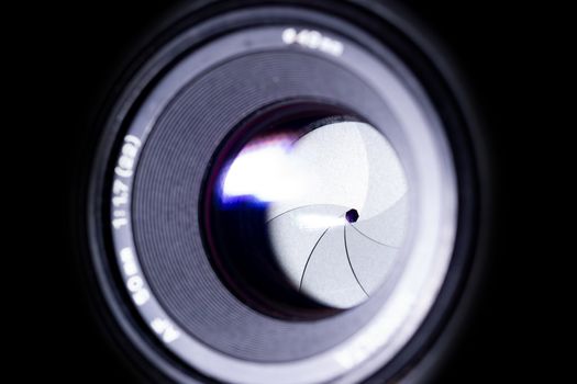 Lens aperture low light photo. Aperture blades is clean. Stock photo with blurred foreground. Isolated on black background.