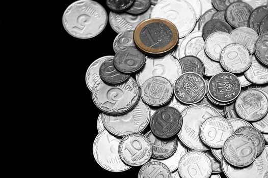 Ukrainian coins with one euro coin isolated on black background. Black and white image.  Euro coin is colored. Close-up view. Coins are located at the right side of frame. A conceptual image.