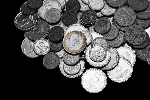 Ukrainian coins with one euro coin isolated on black background. Black and white image.  Euro coin is colored.  Close-up view. Coins are located at the upper side of frame. A conceptual image.